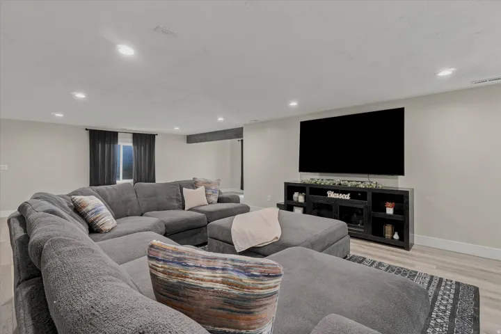 Spacious room featuring recessed lighting, light-toned walls, and wood-finish flooring