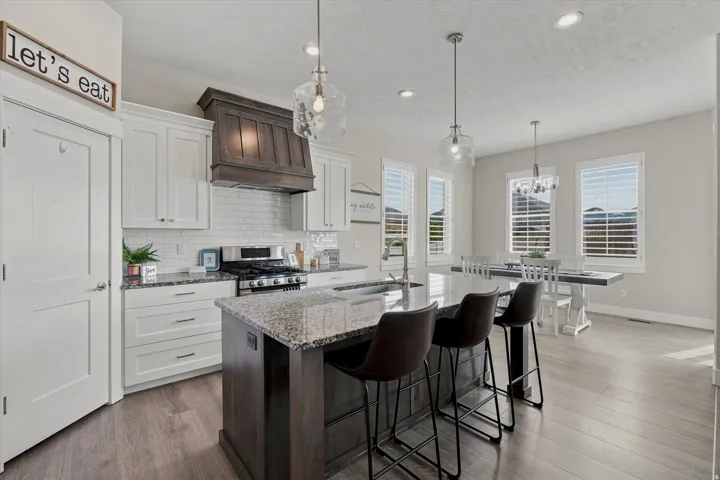 Open-concept kitchen featuring white shaker cabinetry, stainless steel appliances, and wood-finish flooring