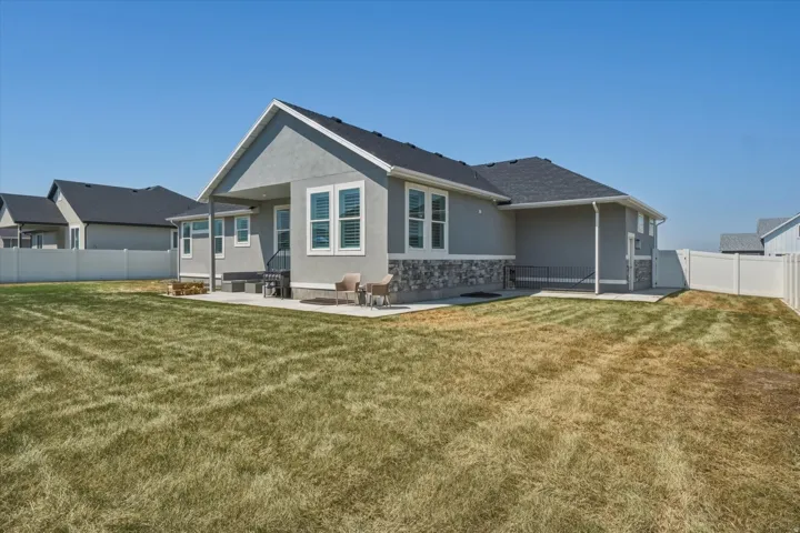 Spacious backyard featuring a concrete patio, stucco exterior with stone accents, and a privacy fence
