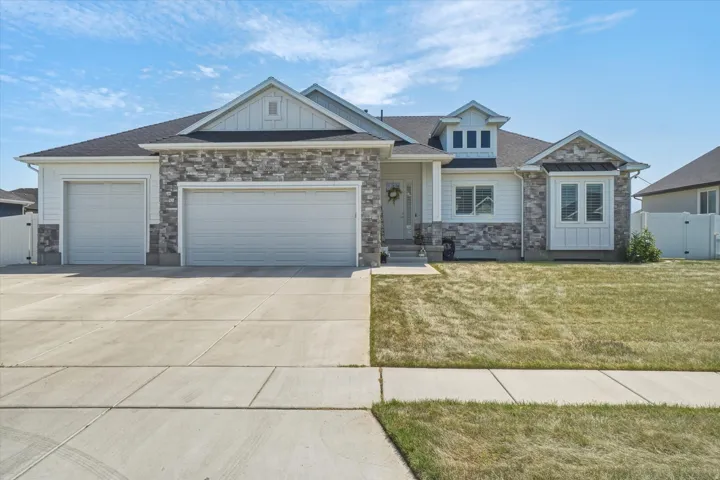 Contemporary exterior featuring a stone and siding facade, a three-car garage, a concrete driveway, a front entry porch, and a bay window