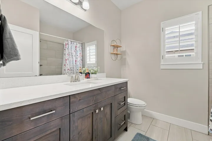 Contemporary bathroom featuring a dark wood-finish vanity with a white countertop and undermount sink