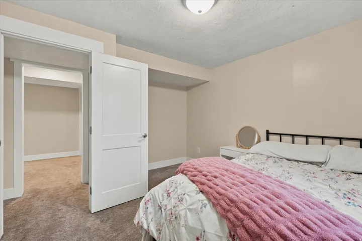 Bedroom featuring neutral tone walls, dark carpet flooring, and white trim