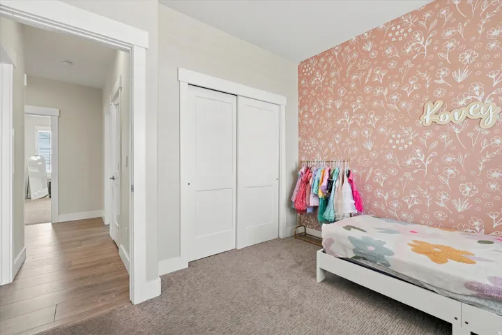 Bedroom featuring a floral accent wall, plush carpeting, and white sliding closet doors