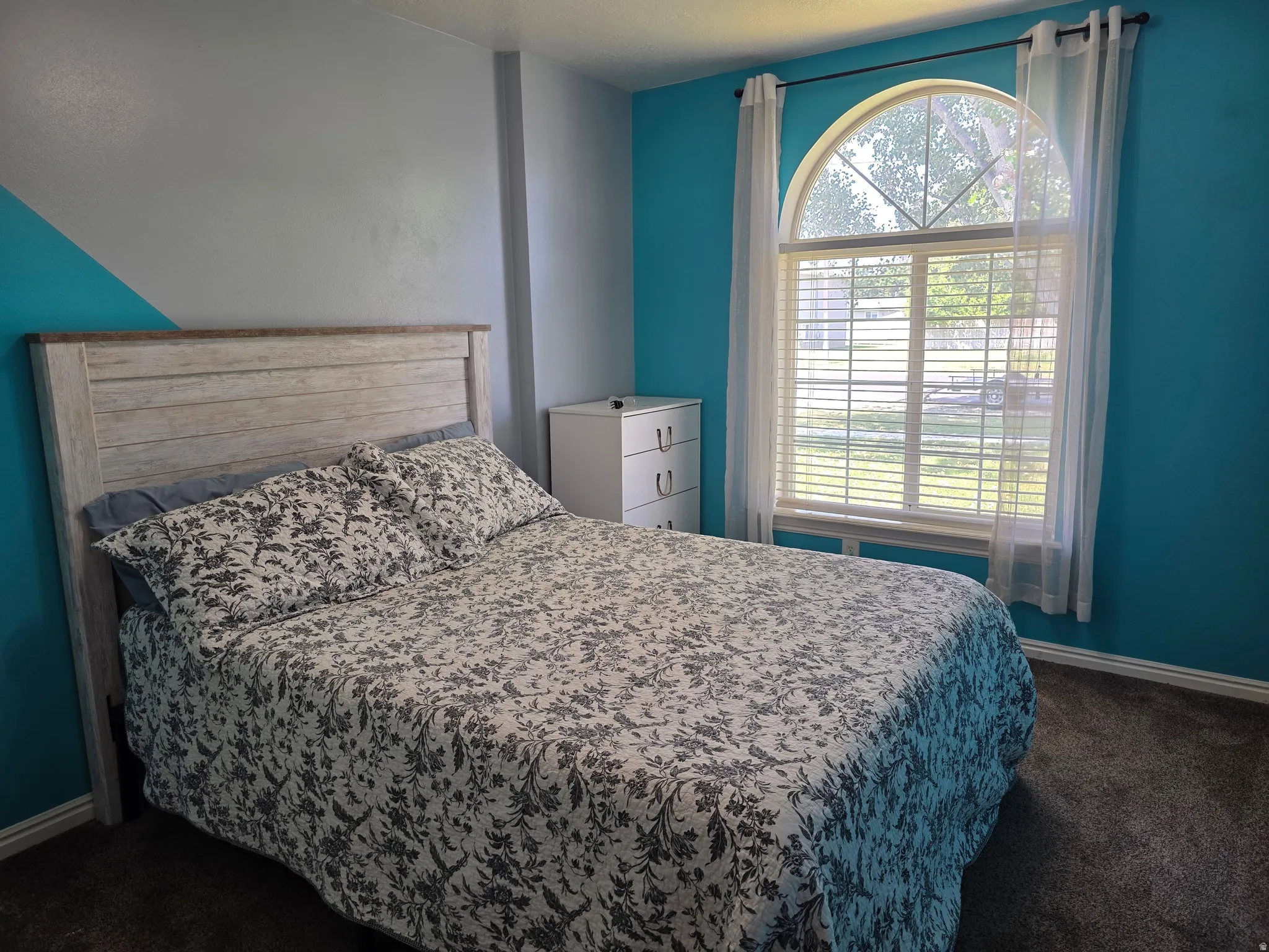 Room featuring an arched window with horizontal blinds, carpet flooring, and a white baseboard trim