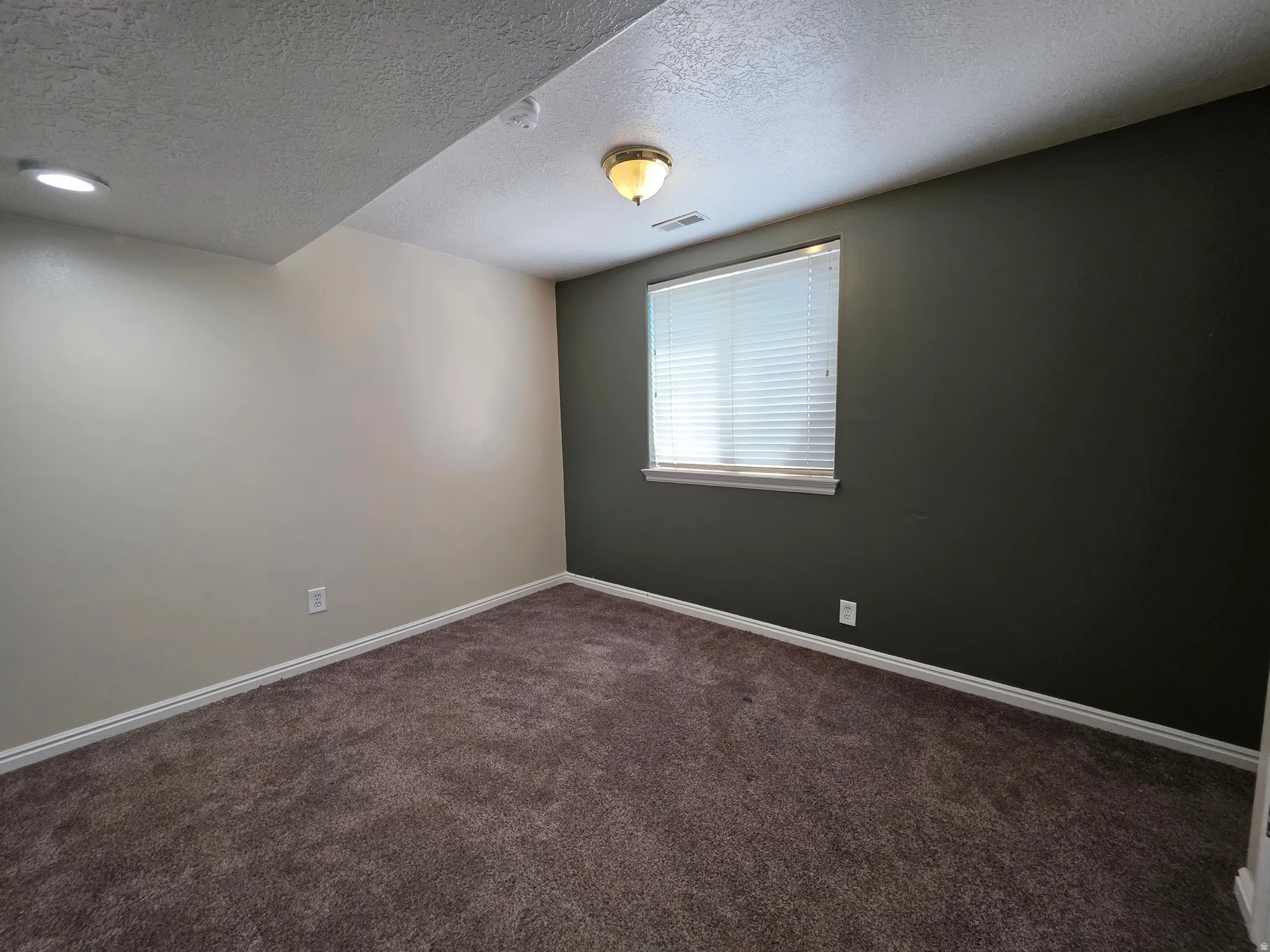 Carpeted room featuring a window with blinds, recessed lighting, and a ceiling-mounted fixture