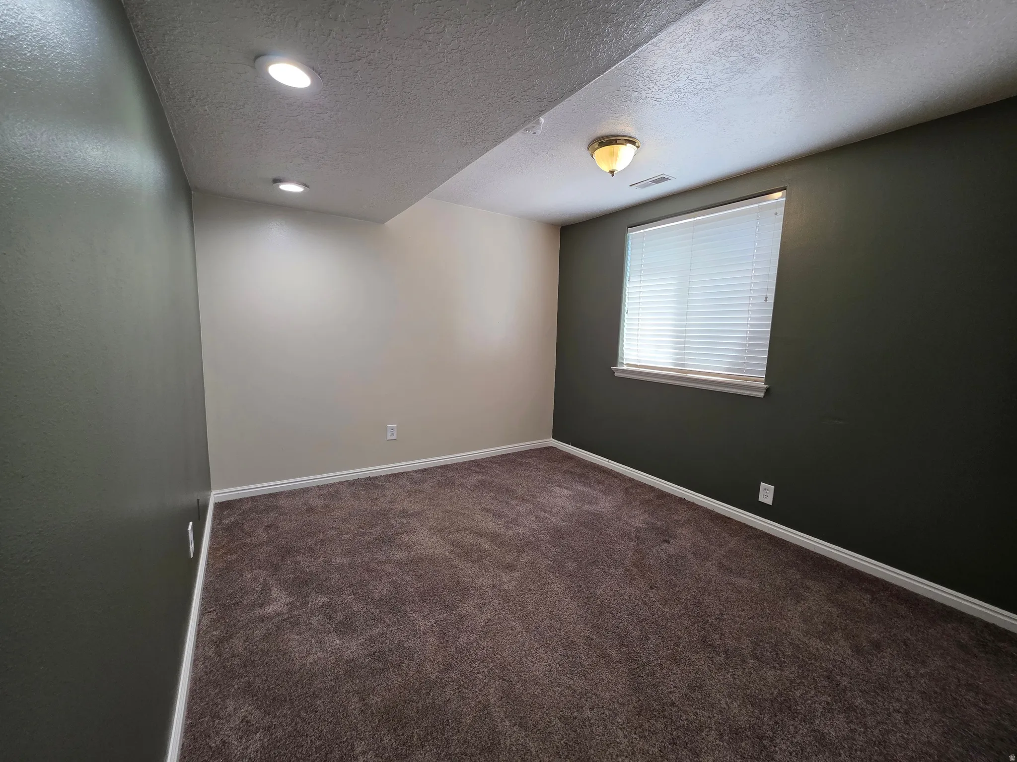 Carpeted room featuring a window with horizontal blinds, a ceiling-mounted light fixture, recessed lighting, and contrasting wall colors
