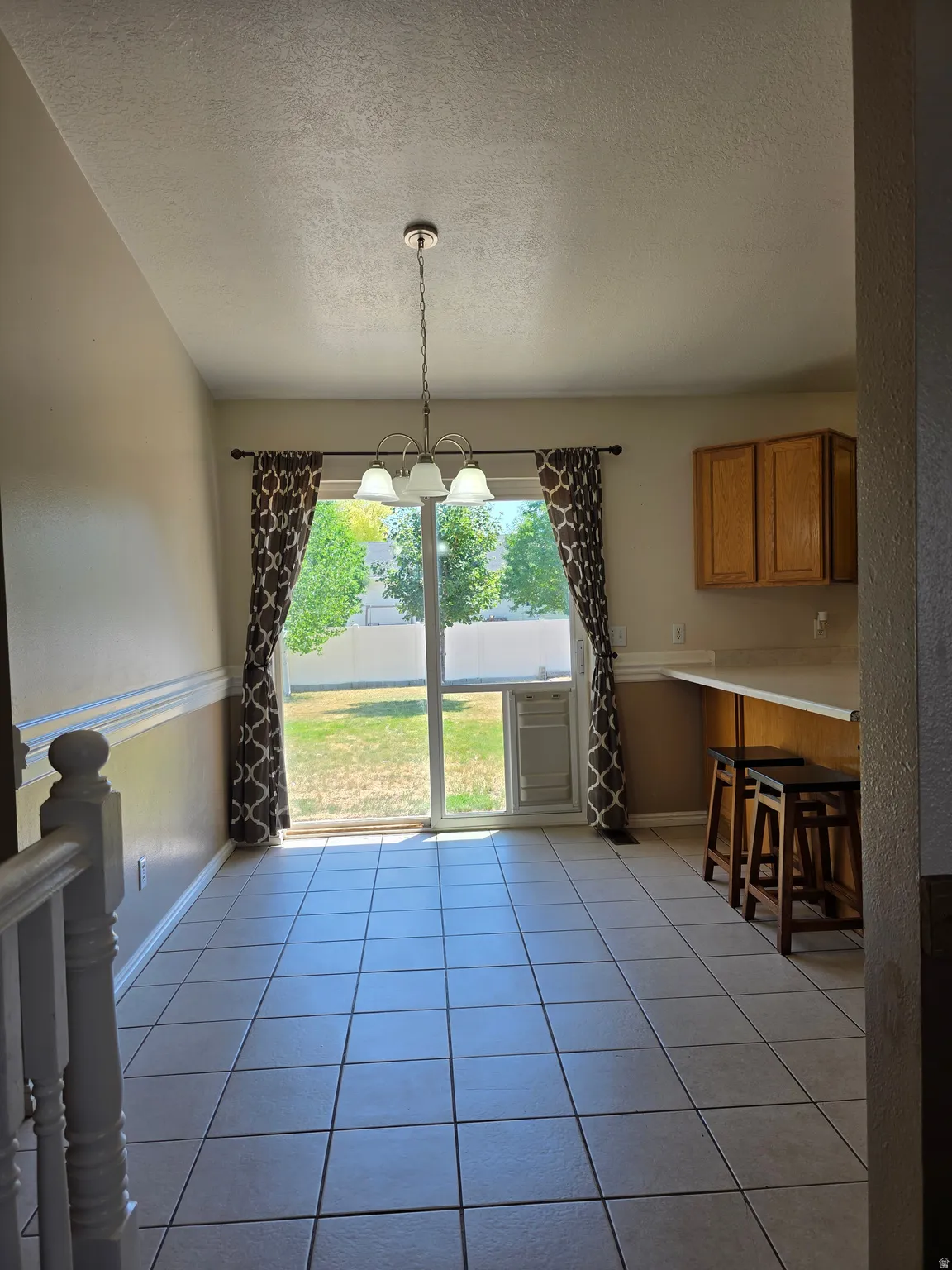 Dining area featuring a sliding glass door to the exterior, overhead chandelier, tile flooring, and a breakfast bar with wood cabinets