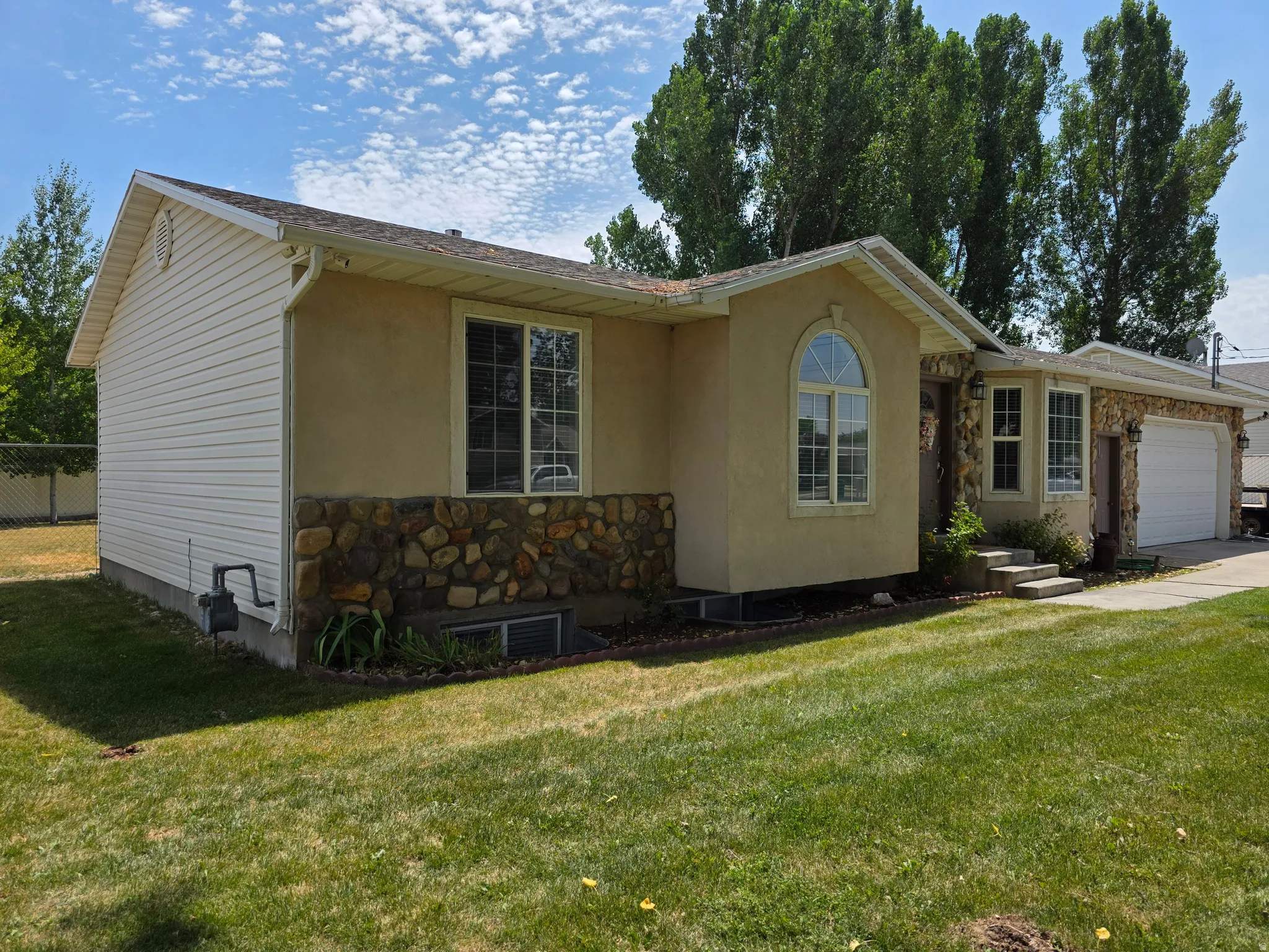 Exterior featuring a combination of stucco and stone veneer, with white horizontal siding on the side elevation
