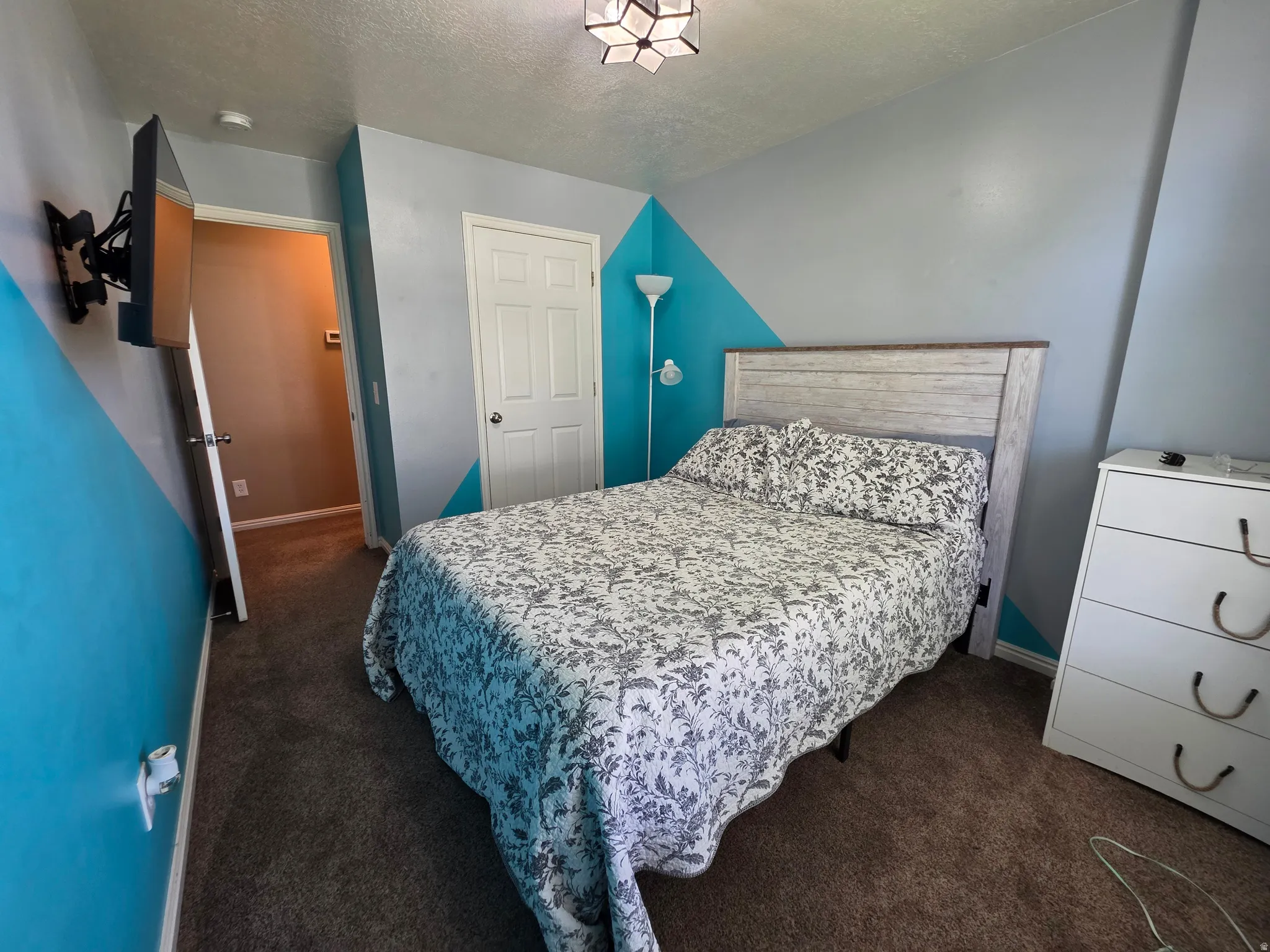Carpeted bedroom featuring a textured gray and blue accent wall