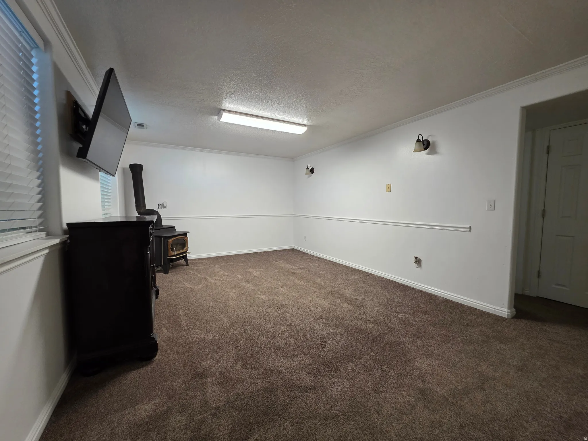 Spacious room featuring neutral carpeting and white walls with chair rail molding