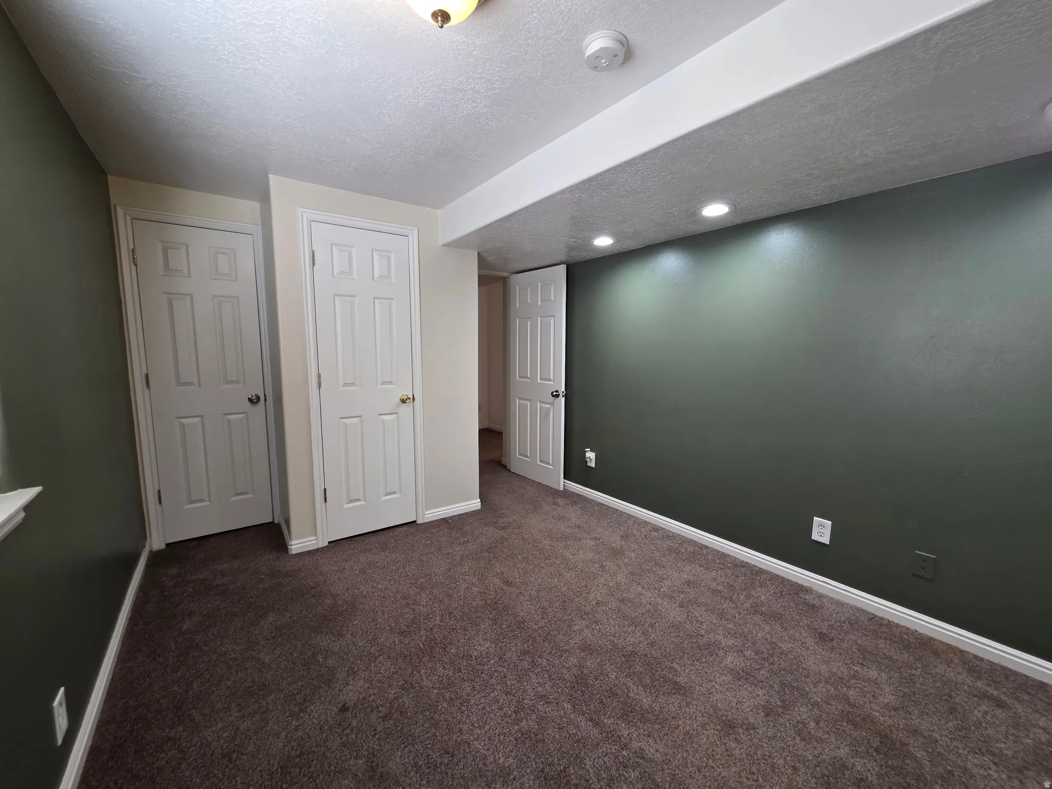 Interior room featuring dark green wall finishes, recessed lighting, white baseboards, and a neutral-toned carpet