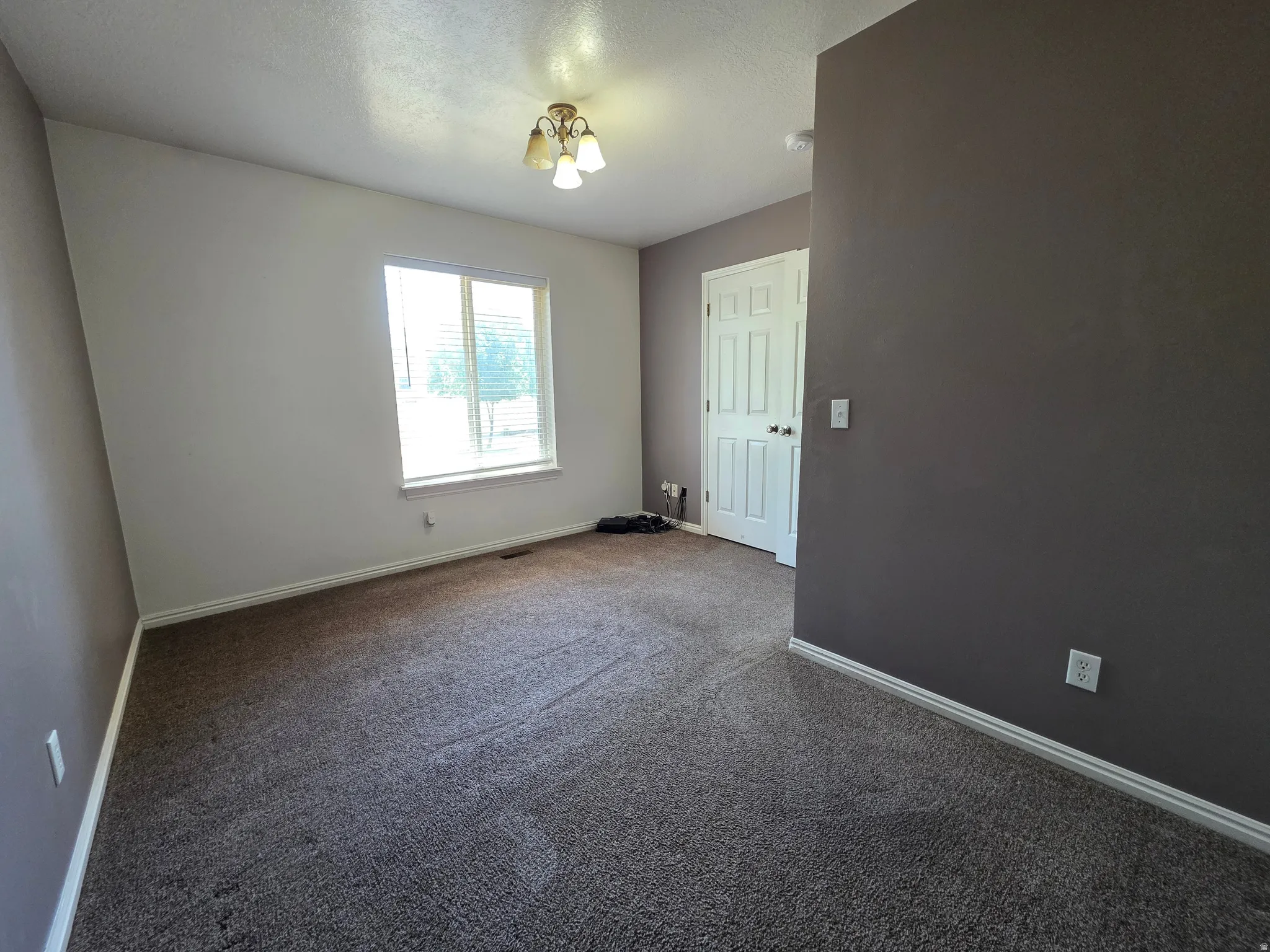 Carpeted room with a multi-pane window featuring blinds