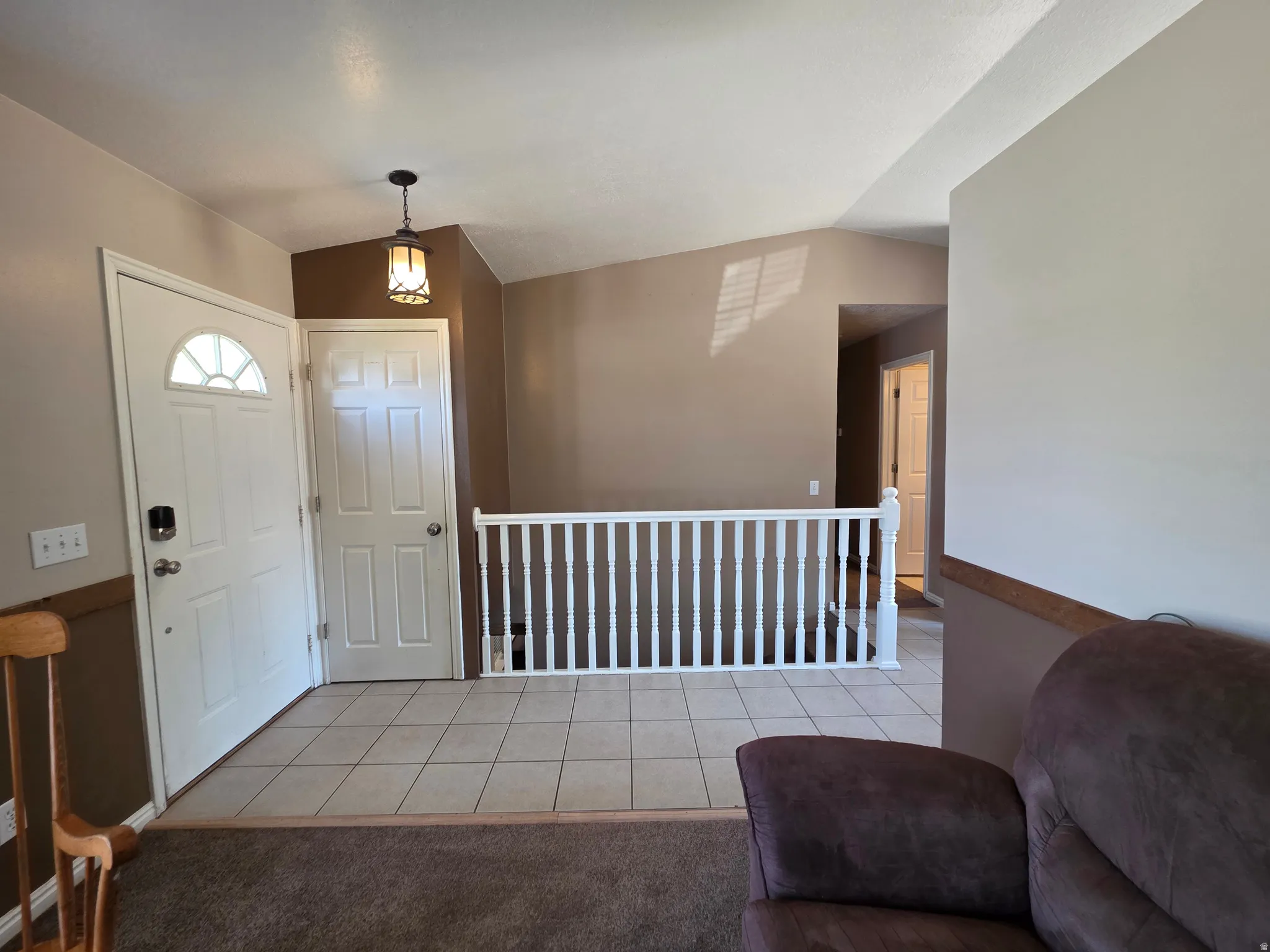 Foyer featuring ceramic tile flooring, a white entry door with an arched window insert, and a contemporary pendant light fixture