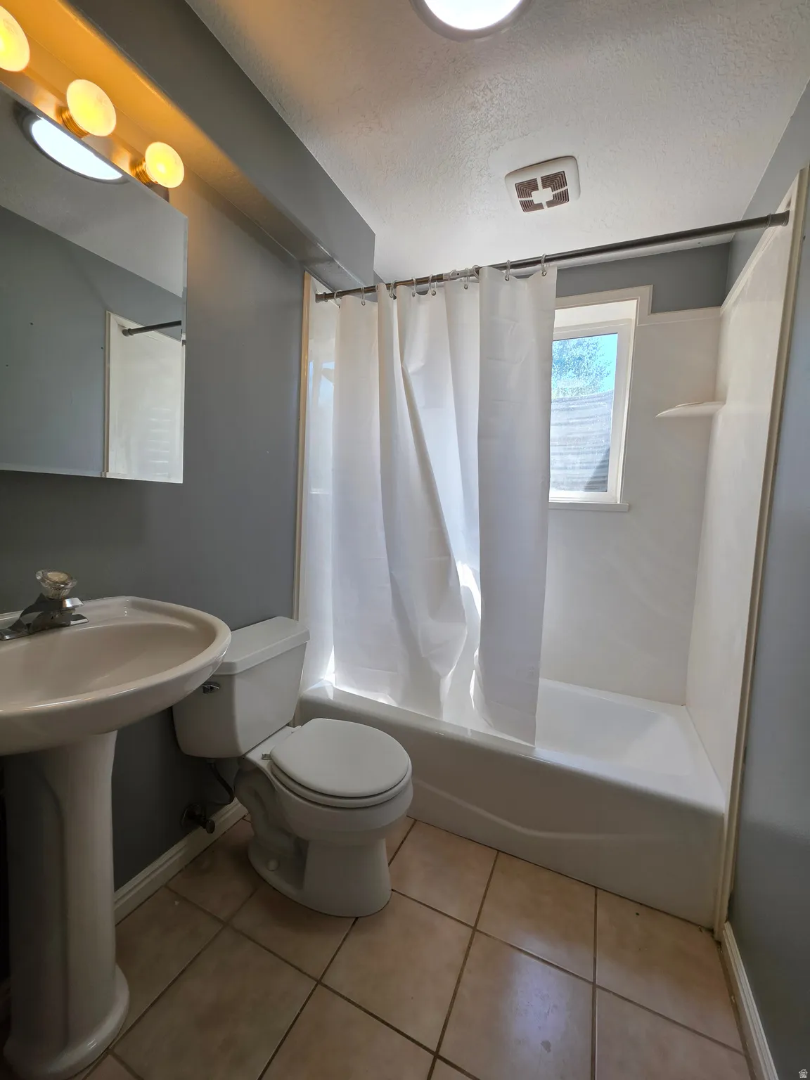 Full bathroom featuring a white pedestal sink, white toilet, and a bathtub with an integrated shower surround