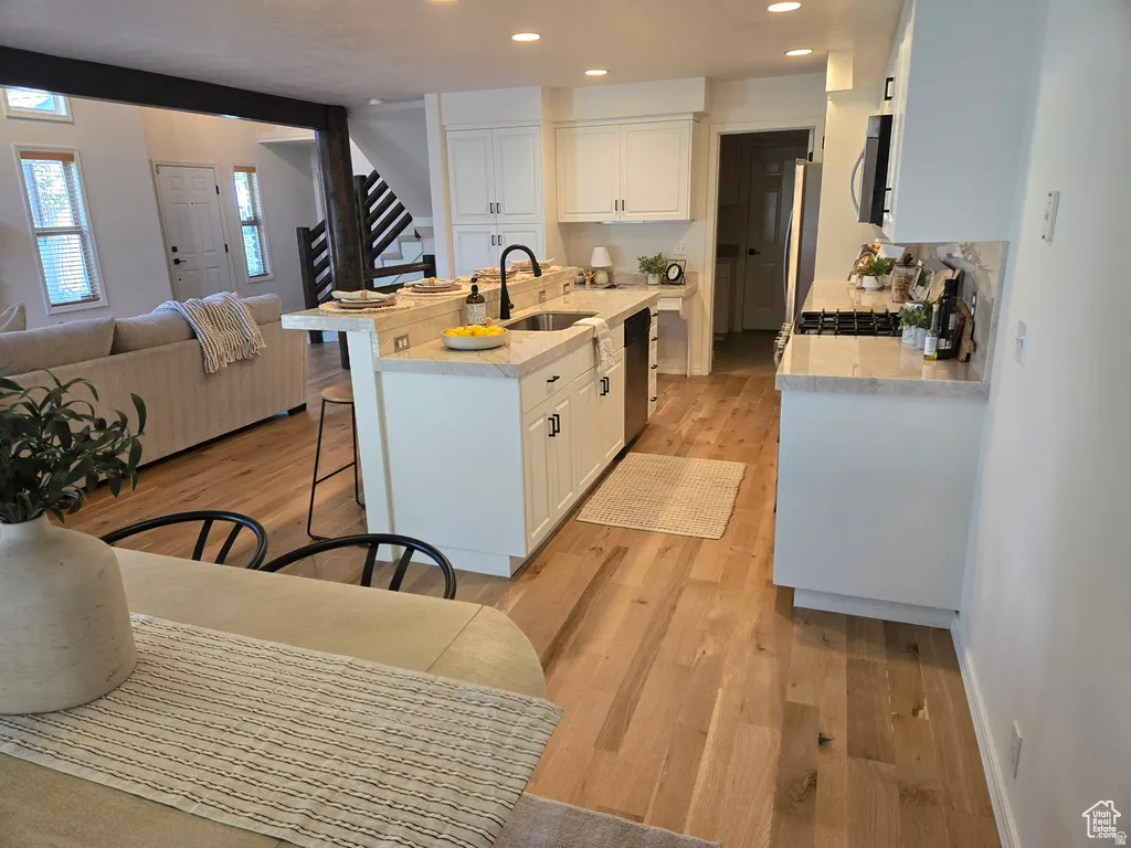 Kitchen with light wood-finish flooring, white cabinetry, and light-colored countertops