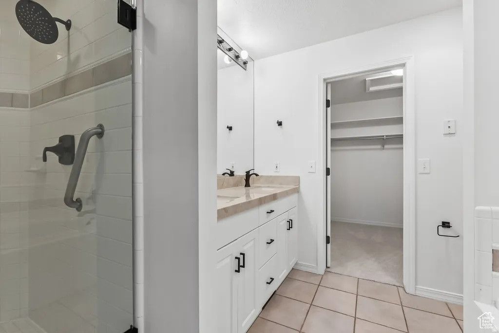 Bathroom featuring a dual vanity with a beige countertop, white cabinetry with black hardware, and an overhead lighting fixture