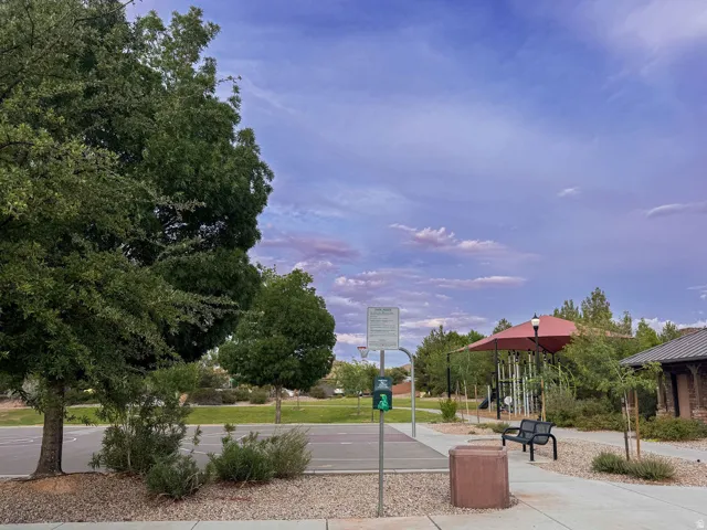 Community basketball court with surrounding landscaping, a shaded play structure, and adjacent pathways