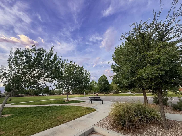 Expansive green space featuring mature trees and a paved walkway