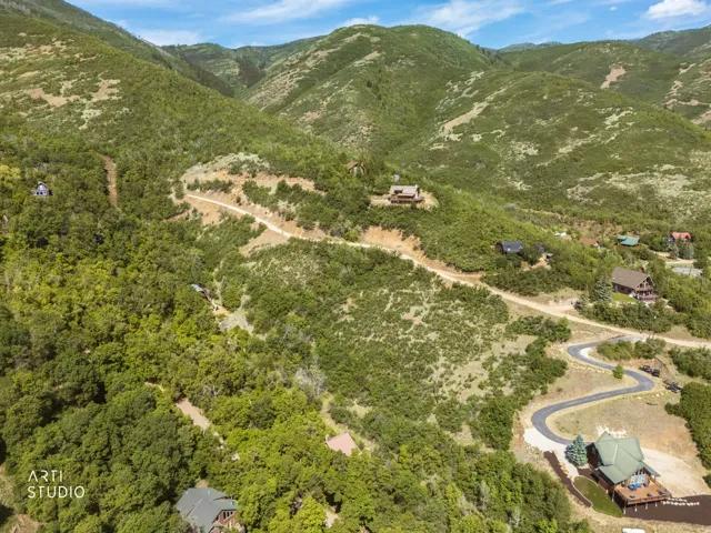 Expansive mountain landscape featuring varied topography with multiple residential structures nestled within the abundant green foliage
