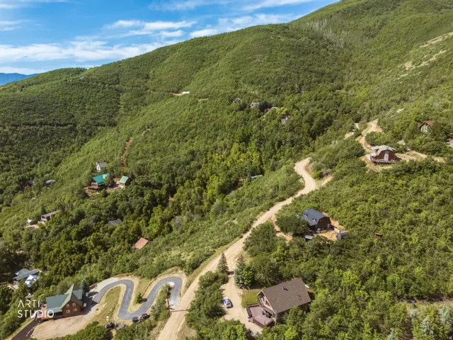 Mountainous terrain with natural landscaping, featuring multiple residential properties nestled among dense trees