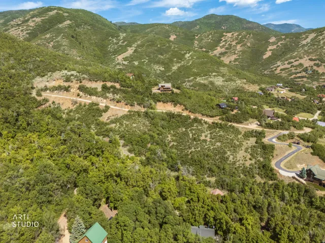 Expansive mountain landscape with diverse terrain and distant residential structures