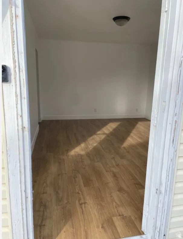 Interior room featuring wood-finish flooring, white painted walls, and a ceiling-mounted light fixture