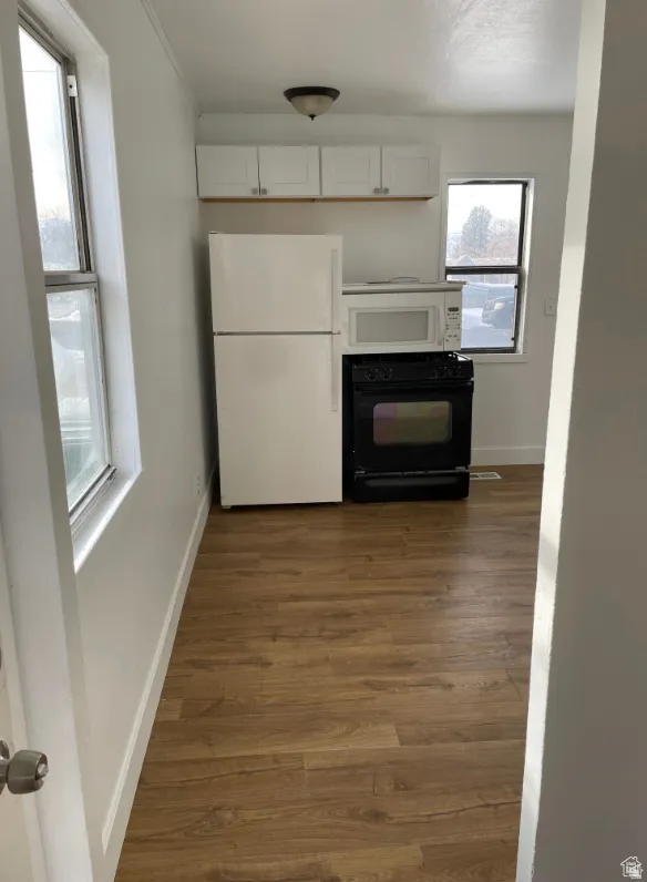 Kitchen space featuring wood-finish flooring, white cabinetry, and white walls