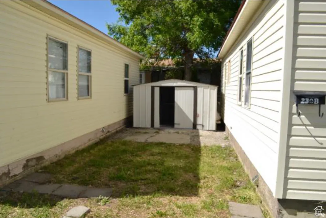 Compact side yard featuring a metal storage shed on a concrete pad, flanked by two buildings with horizontal siding