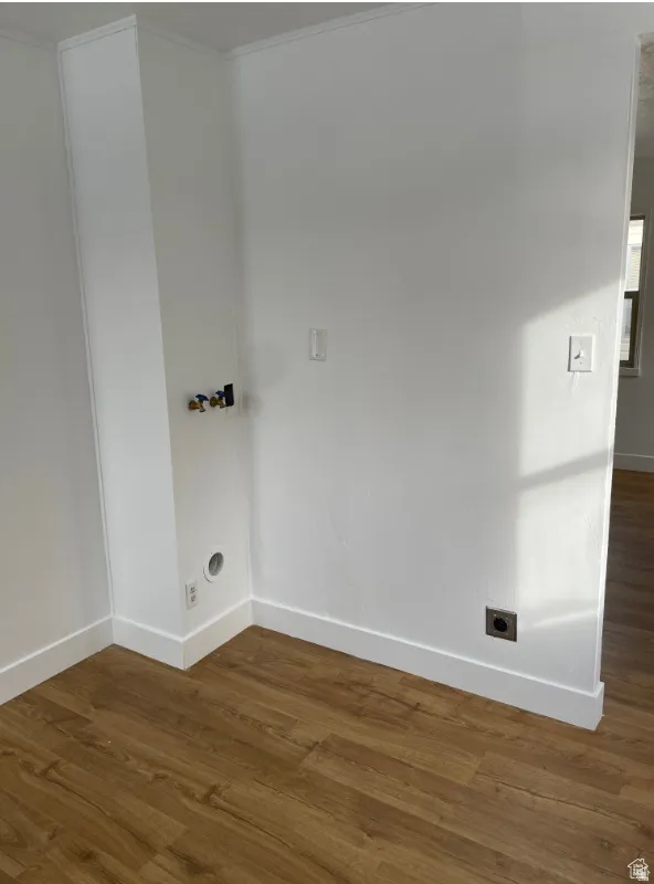 Dedicated laundry area featuring wood-finish flooring, white walls, and bright white baseboards