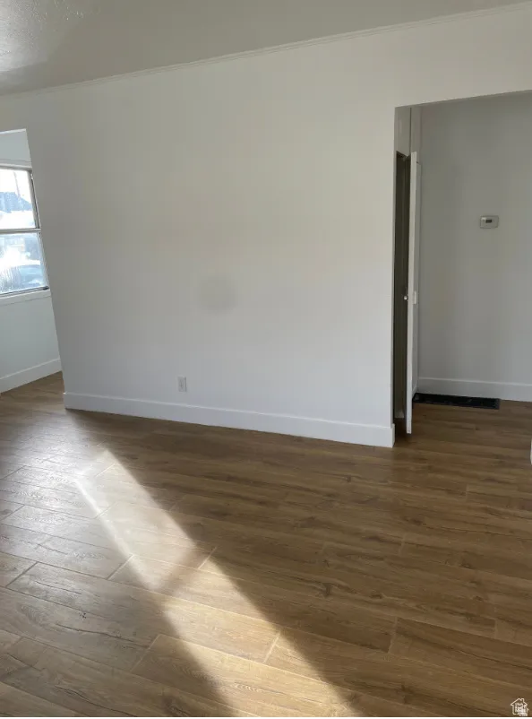 Wood-finish flooring throughout, complemented by white baseboards and crown molding
