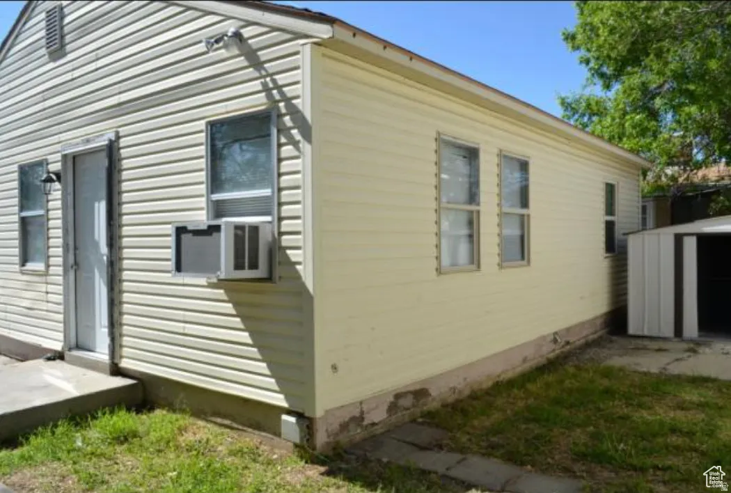 Exterior featuring horizontal siding, multiple windows, an exterior door, and a metal storage shed