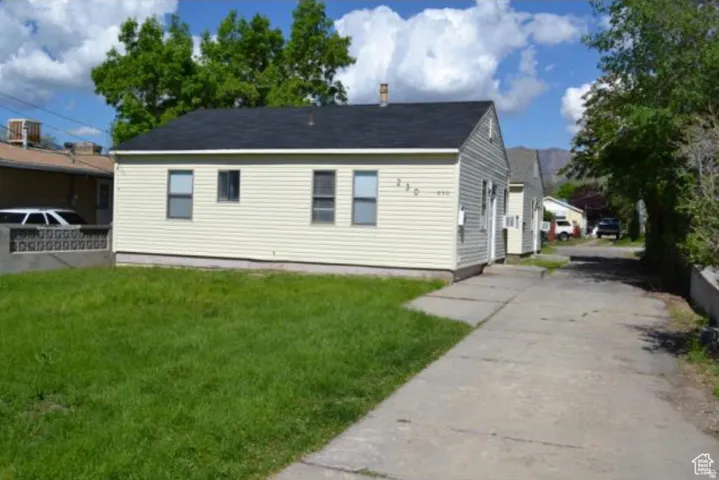Single-story residence featuring light-colored siding, a dark shingle roof, and a front lawn