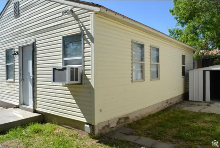 Exterior featuring horizontal siding, multiple windows, an exterior door, and a metal storage shed