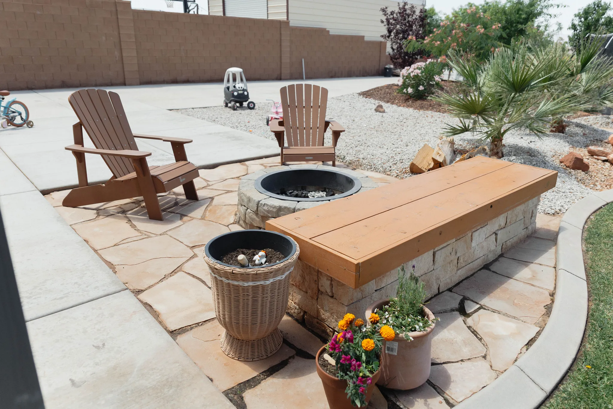 Outdoor hardscaping featuring a built-in stone fire pit, a stone-faced bench with a wood-finish top, and irregular flagstone patio