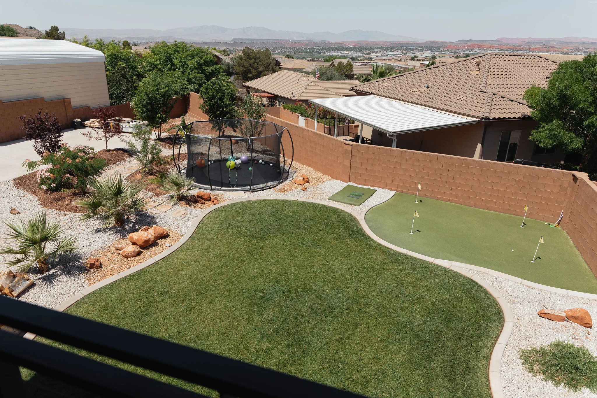 Expansive backyard featuring a green lawn, a dedicated putting green with multiple holes, and a desert-style landscape with gravel and mature plantings