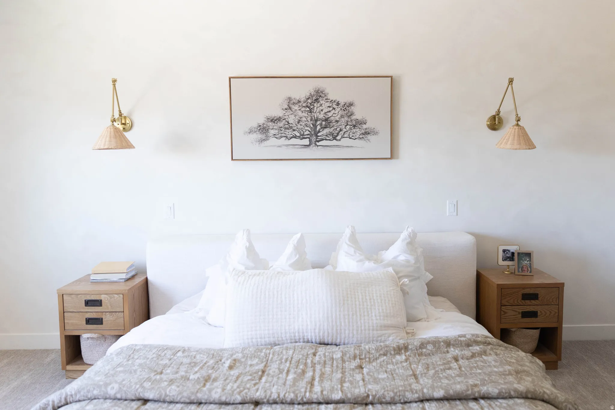 Bedroom featuring a white upholstered headboard, paired with wood-finish nightstands with dark hardware
