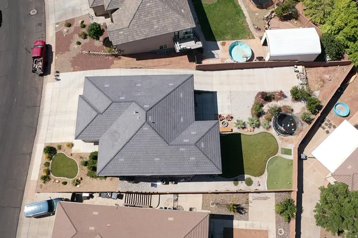 Property with a multi-gabled roofline, extensive paved driveway, and a backyard featuring a putting green, synthetic turf, and desert landscaping