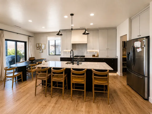 Expansive kitchen featuring a large island with seating, stainless steel appliances, wood-finish flooring, and ample cabinetry