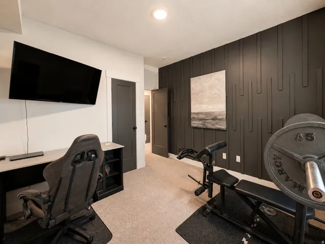 Carpeted interior space featuring a dark accent wall with vertical paneling, recessed lighting, and dark-toned interior doors