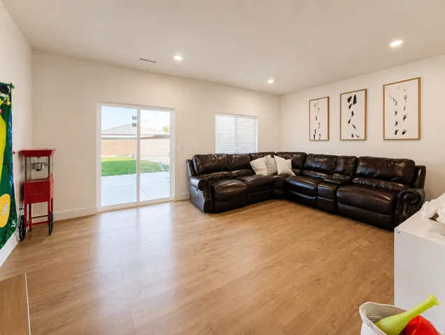Vaulted ceiling with recessed lighting, wood-finish flooring, sliding glass door, and a window with blinds