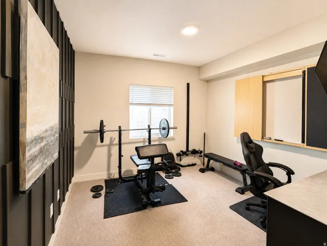 Recessed lighting illuminates the room, featuring a window with blinds, carpeted flooring, and a built-in wall unit