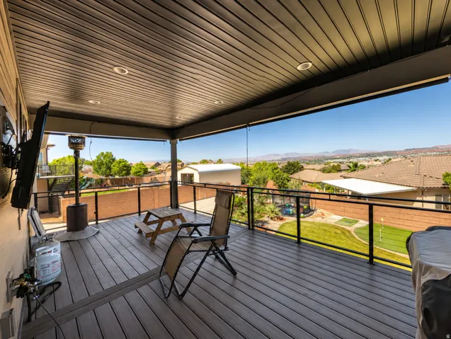Spacious covered deck featuring composite decking, recessed lighting, and a glass panel railing