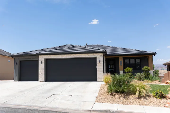 Modern single-story residence featuring a stone and wood facade, black-frame windows, a dark roof, and a multi-car garage with black doors