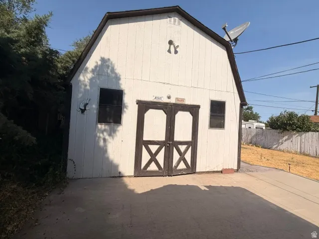 Gambrel-style outbuilding featuring double barn doors with X-brace detailing and two rectangular windows