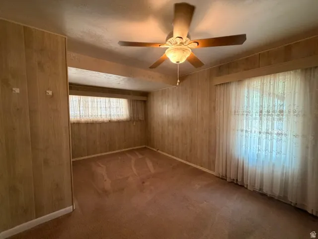 Room featuring wood-look paneling, a ceiling fan, and carpeted flooring