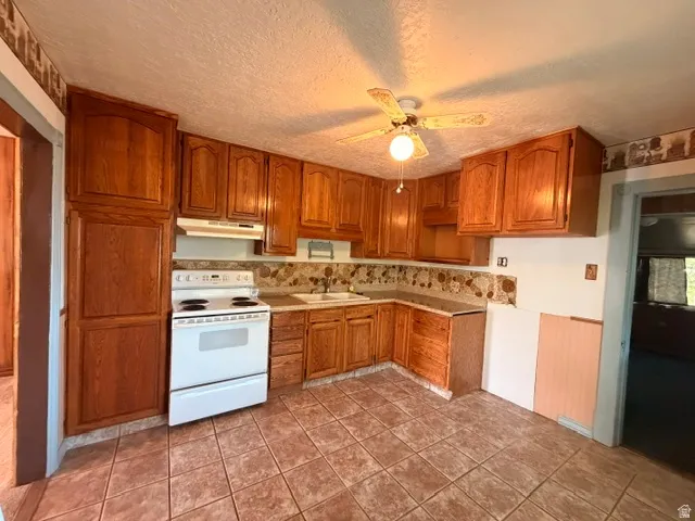 Kitchen featuring wood cabinetry, white electric range, and tile flooring