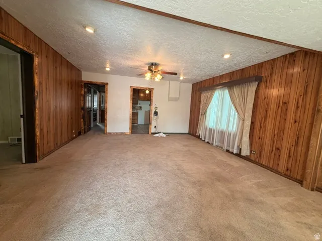 Spacious room featuring wood paneling, recessed lighting, and a ceiling fan