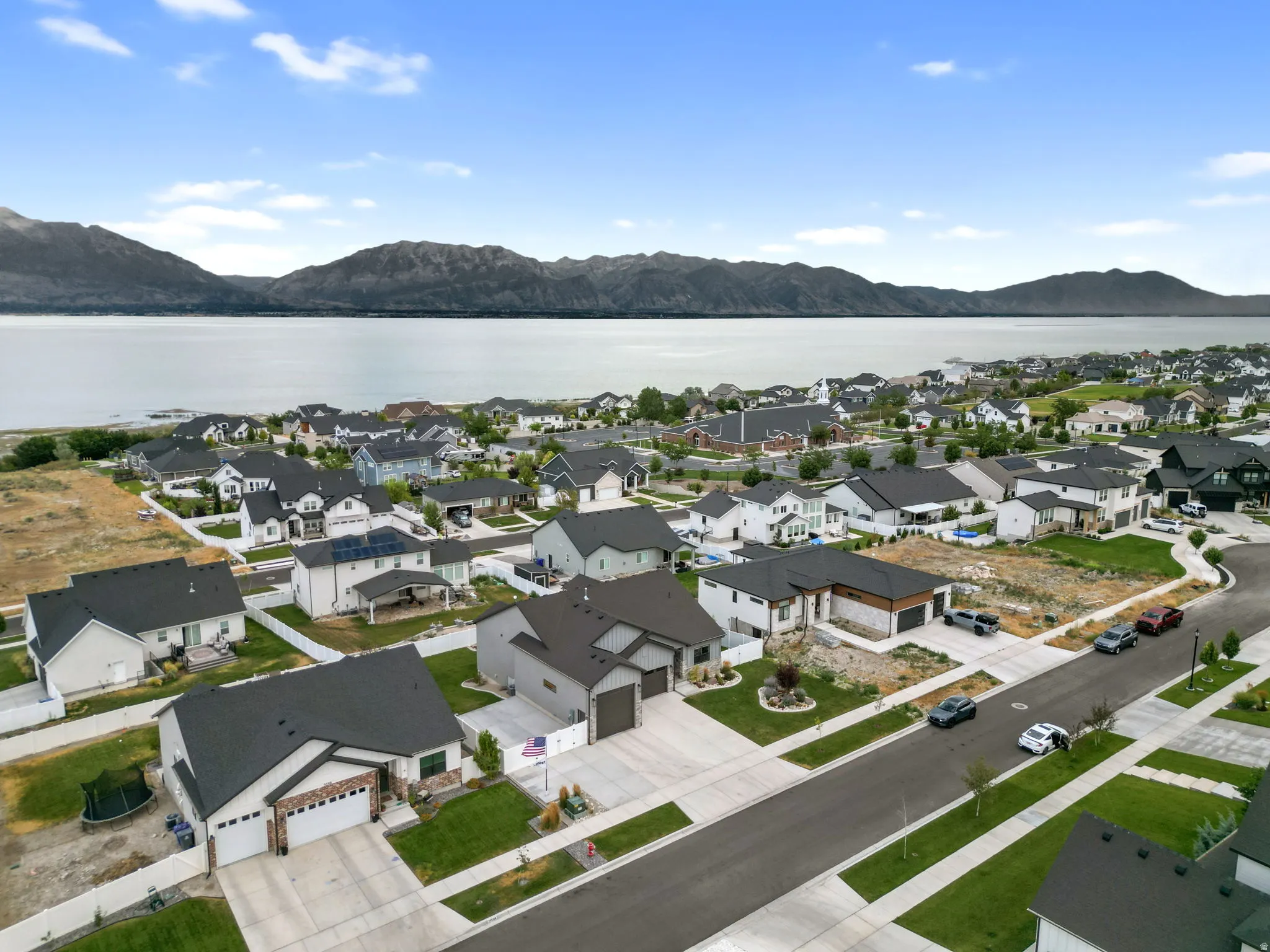 Aerial perspective showcasing a residential community with a large body of water and mountains in the background