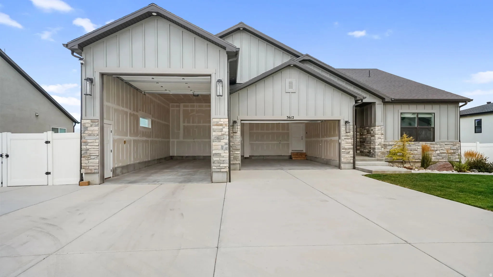 Contemporary exterior featuring board and batten siding, stone accents, and a multi-car driveway