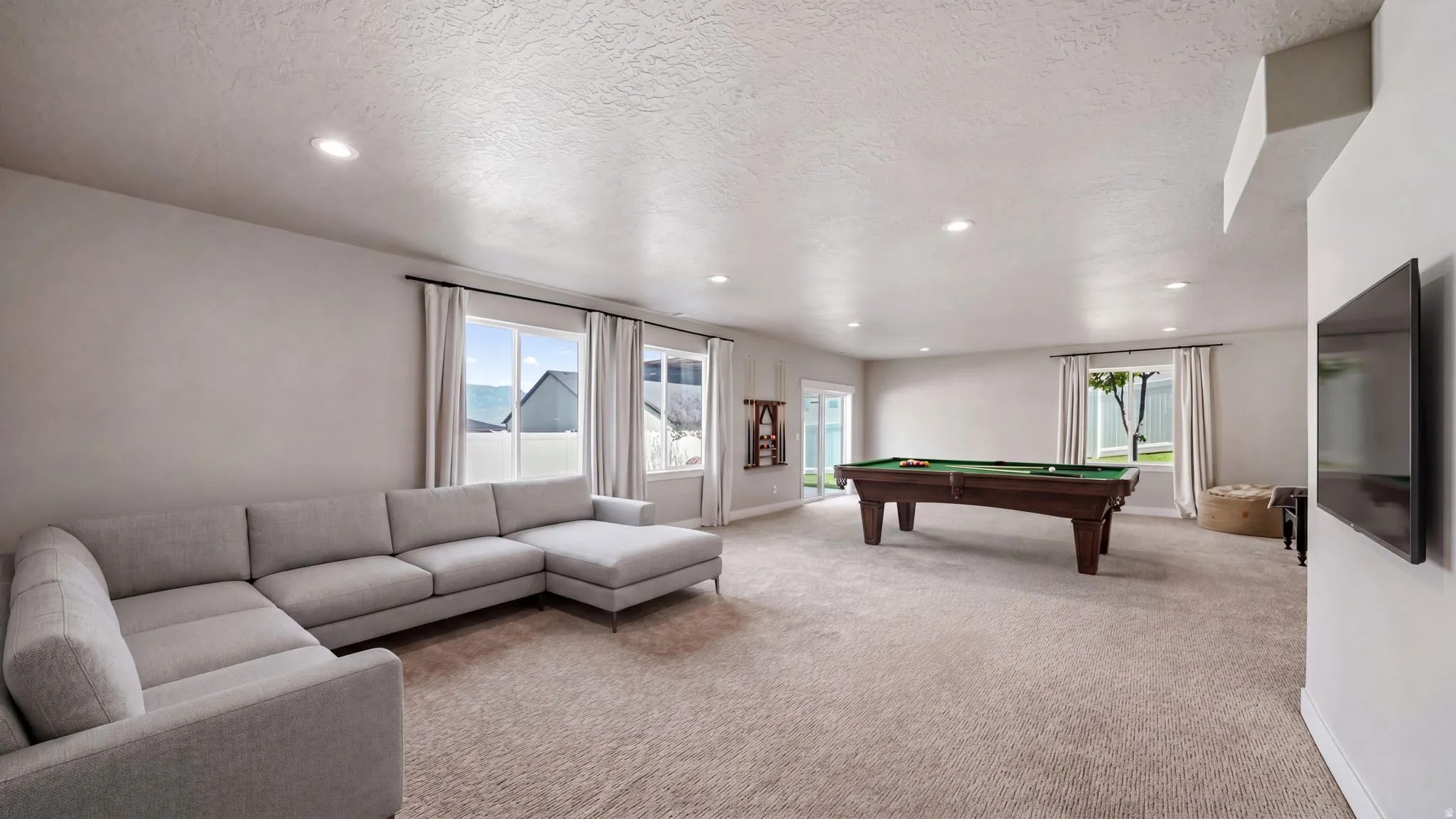 Spacious recreation room featuring recessed lighting, multiple windows with natural light, and neutral-toned carpeting